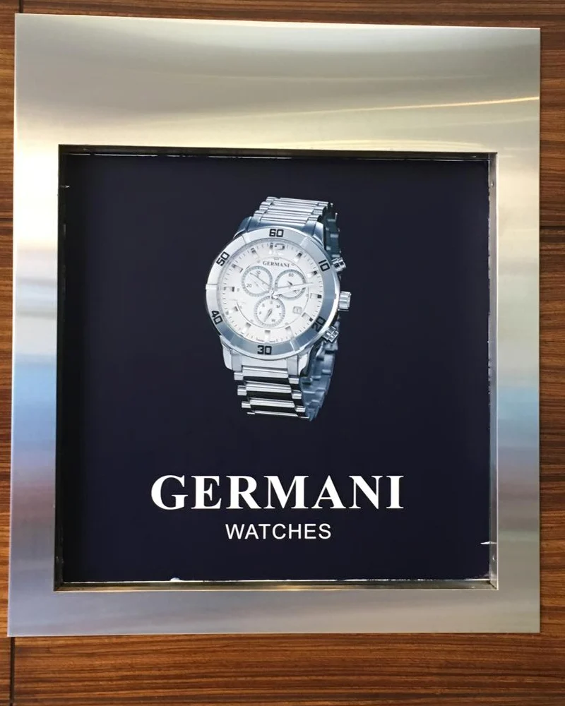A framed Germani Watches display panel set into a wooden wall
