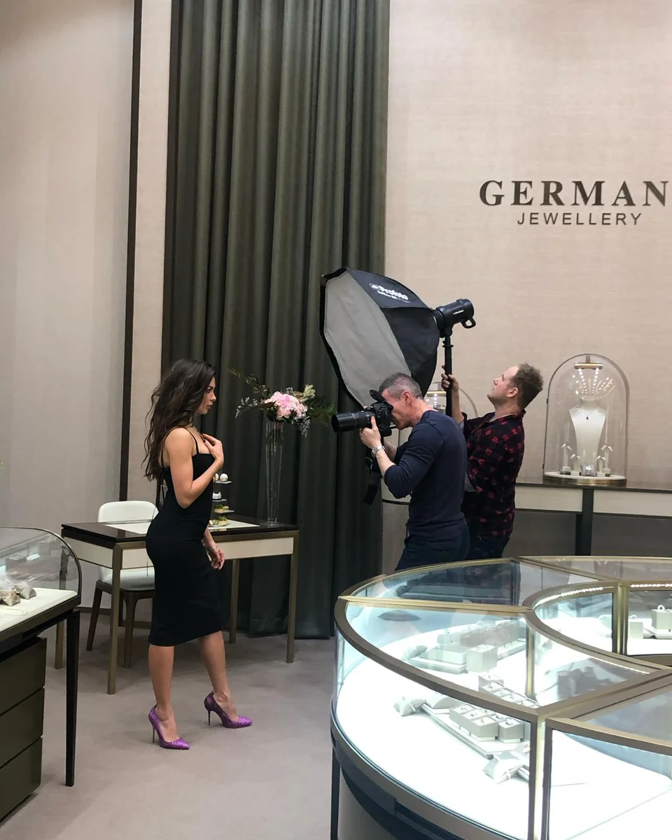 Photographer and lighting assistant shooting a model beneath the Germani Jewellery sign