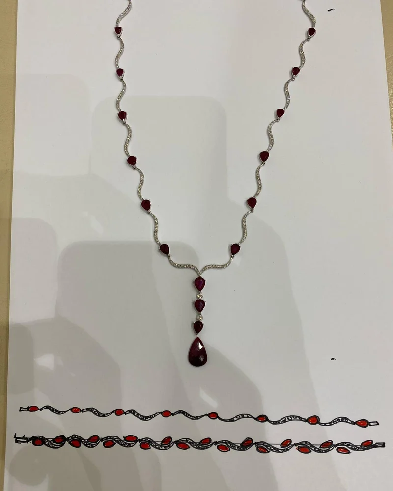 The ruby necklace laid above hand sketches of its matching ruby bracelets