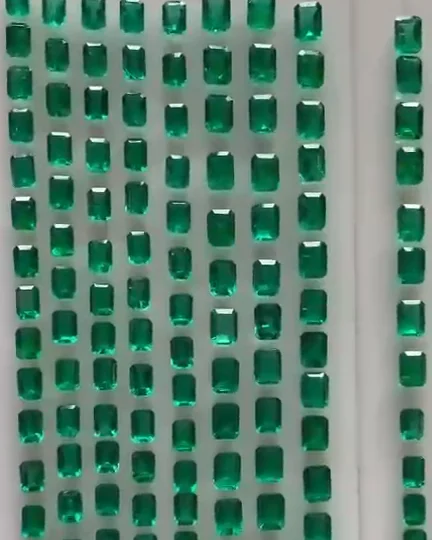Rows of loose natural emeralds laid out for selection