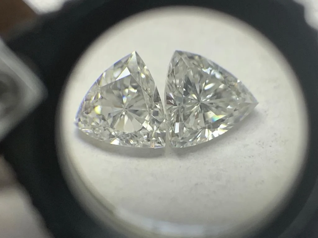 A matched pair of triangle-shaped diamonds under a loupe