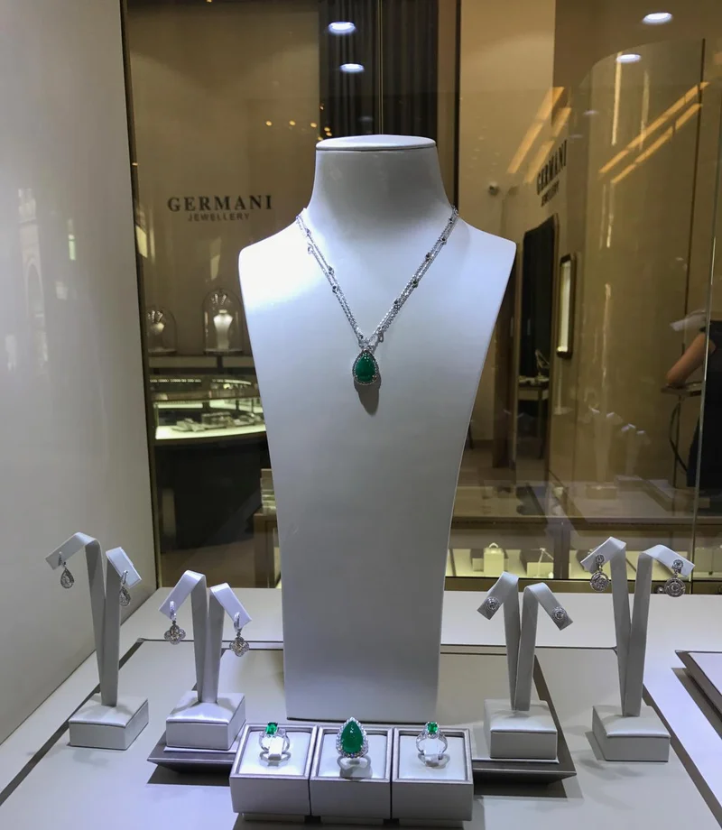 Germani window display with an emerald pendant, emerald rings and diamond earrings